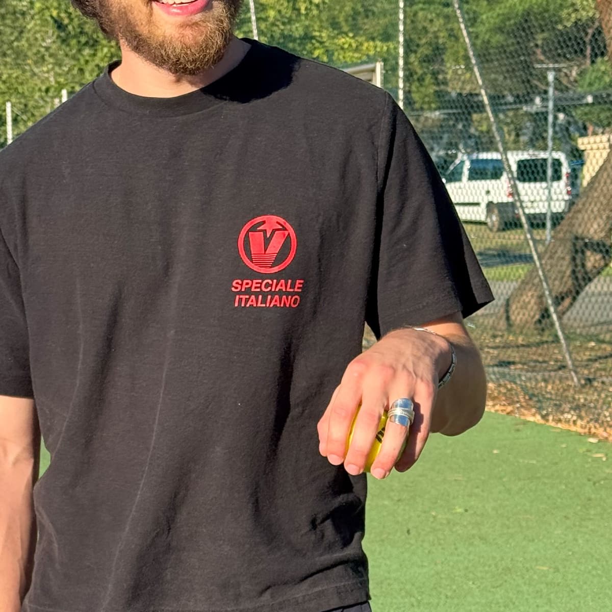 A spoon ring worn on a hand holding a tennis ball