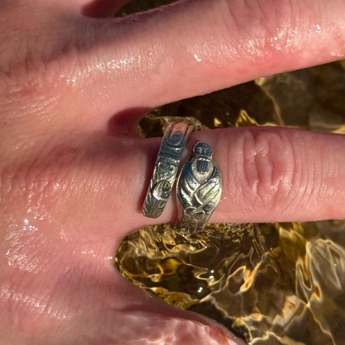 A spoon ring with an apostle figure on a wet finger above water